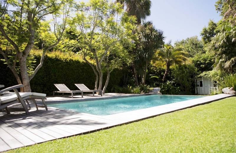 Aménagement paysager autour d'une piscine avec massifs de fleurs, palmiers et éclairage pour un cadre apaisant et convivial près d'Aix en Provence